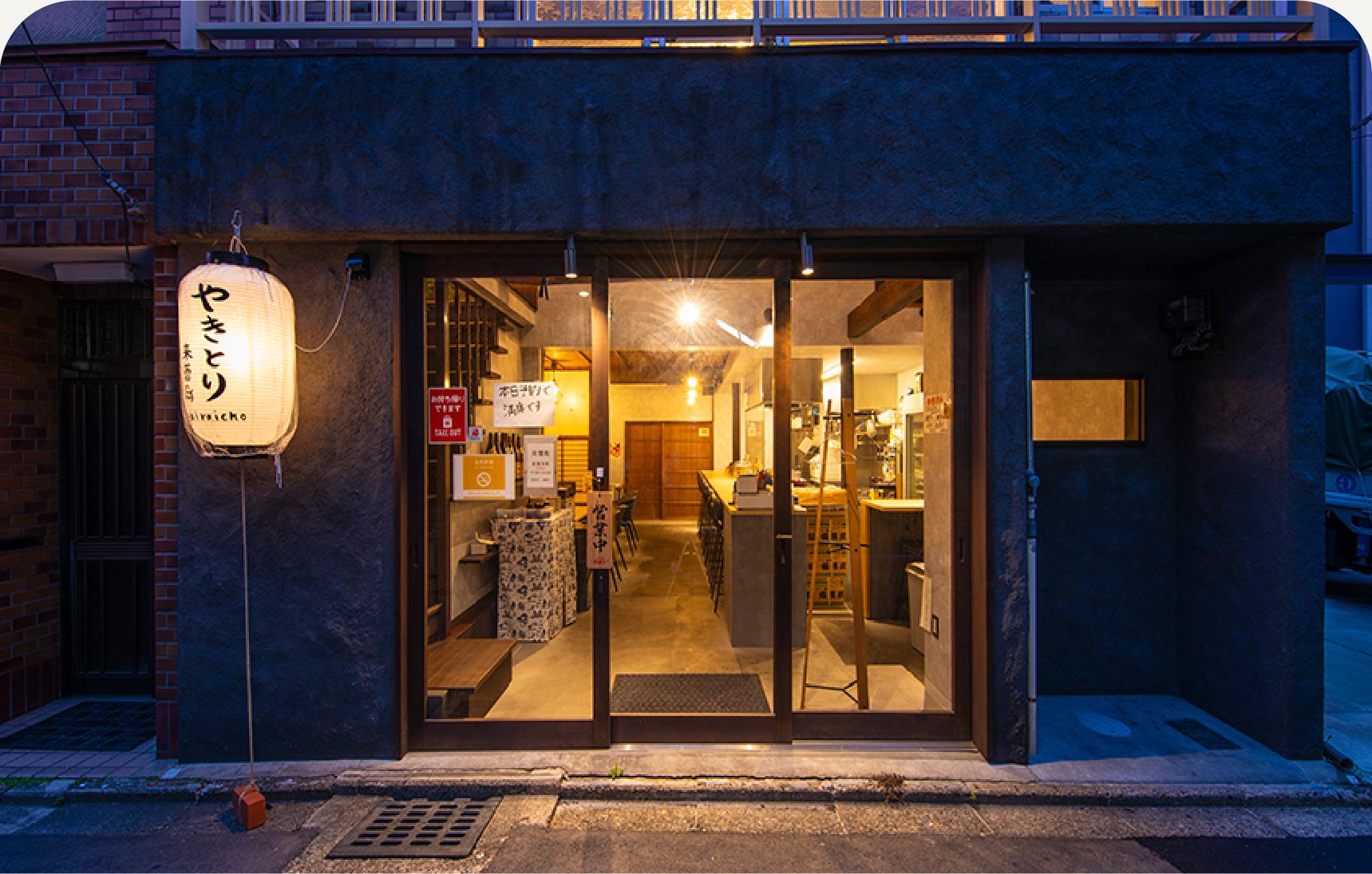 活用後：提灯が灯り、ガラス戸から店内の明かりがこぼれる夜の店舗の外観